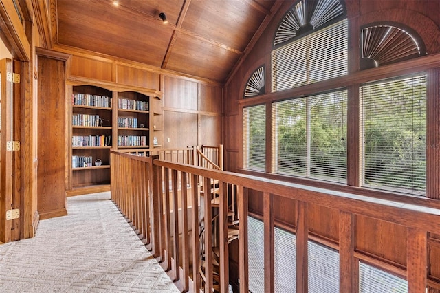 corridor with wooden walls, a wealth of natural light, and wooden ceiling