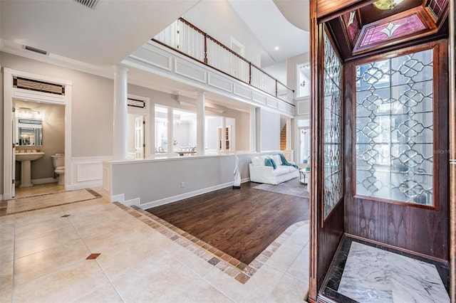 foyer entrance with sink, hardwood / wood-style floors, decorative columns, and vaulted ceiling