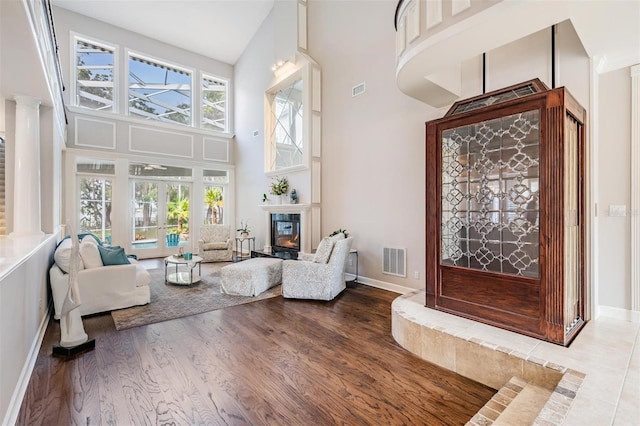 interior space with ornate columns, high vaulted ceiling, plenty of natural light, and wood-type flooring