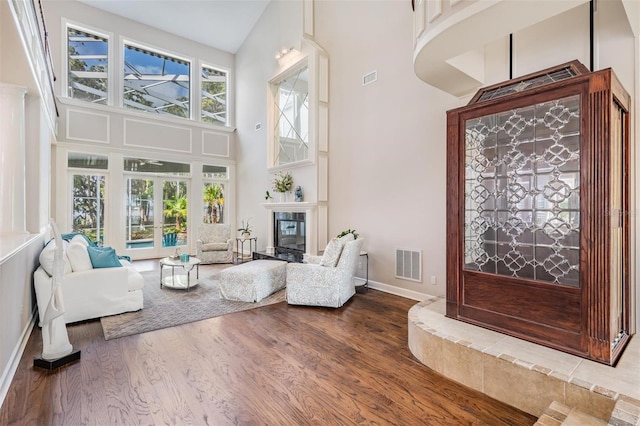 sitting room featuring hardwood / wood-style flooring, a tiled fireplace, and high vaulted ceiling