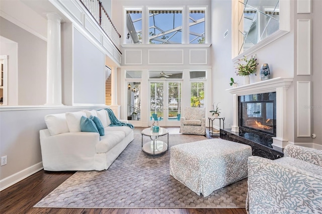 living room featuring a fireplace, dark hardwood / wood-style floors, a high ceiling, and crown molding