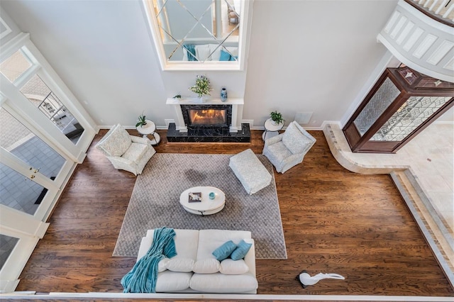 living room with a fireplace, dark hardwood / wood-style flooring, and a towering ceiling