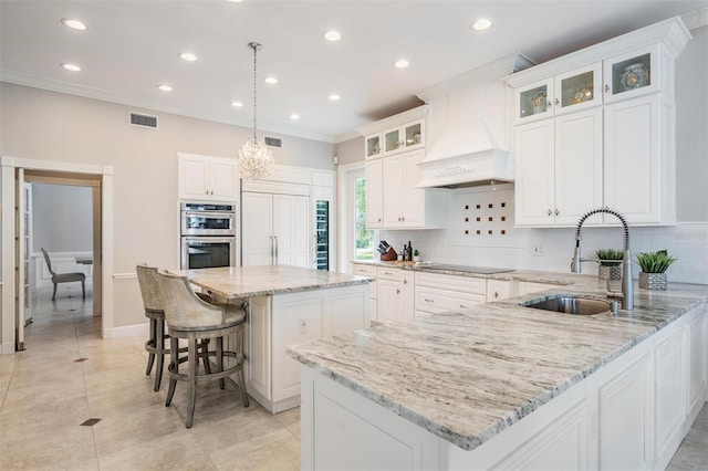 kitchen with tasteful backsplash, sink, custom exhaust hood, double oven, and a center island