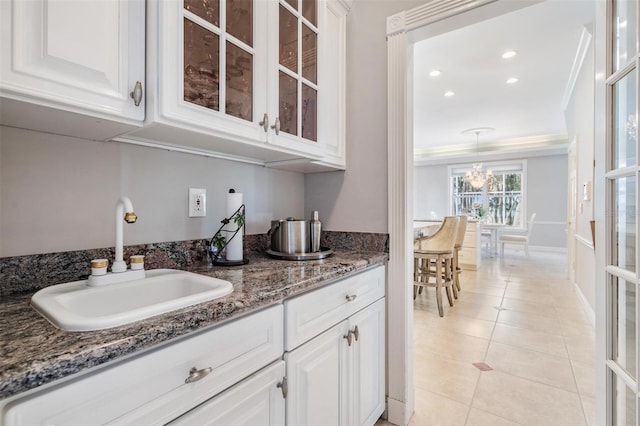 bar featuring pendant lighting, dark stone counters, sink, and white cabinets