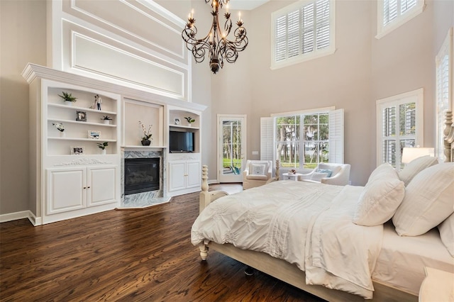 bedroom featuring dark wood-type flooring, a high ceiling, access to exterior, and a chandelier