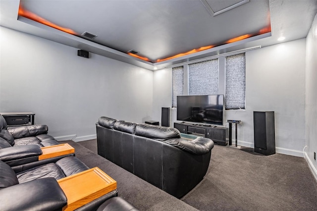 cinema featuring a tray ceiling and dark colored carpet