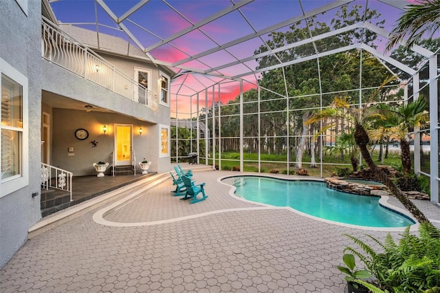 pool at dusk featuring a lanai, an in ground hot tub, and a patio area