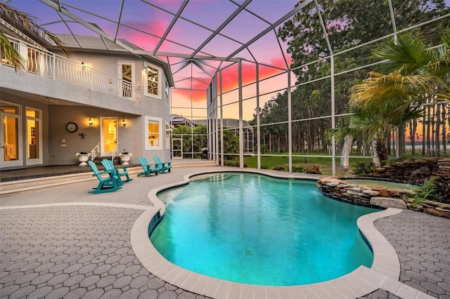 pool at dusk with a patio and glass enclosure