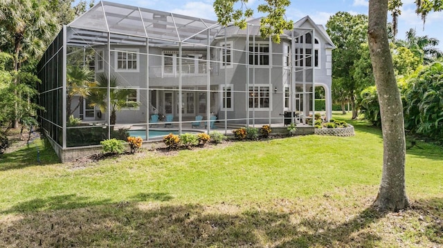 rear view of house with a patio, a lawn, and a lanai