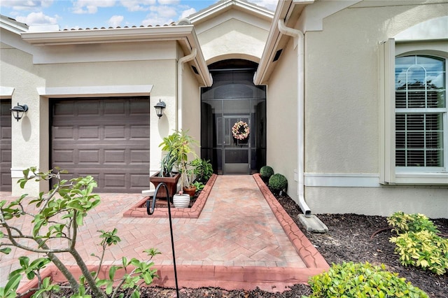 entrance to property featuring a garage and stucco siding