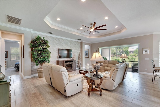living room featuring a fireplace, visible vents, ceiling fan, and a raised ceiling
