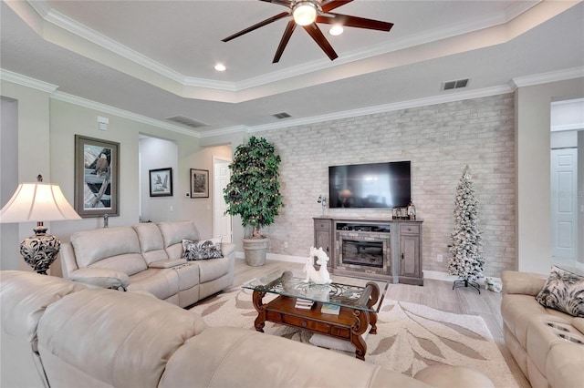 living room with crown molding, ceiling fan, light wood-type flooring, and a tray ceiling