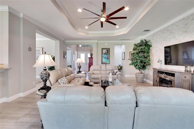 living room with crown molding, a tray ceiling, and ceiling fan