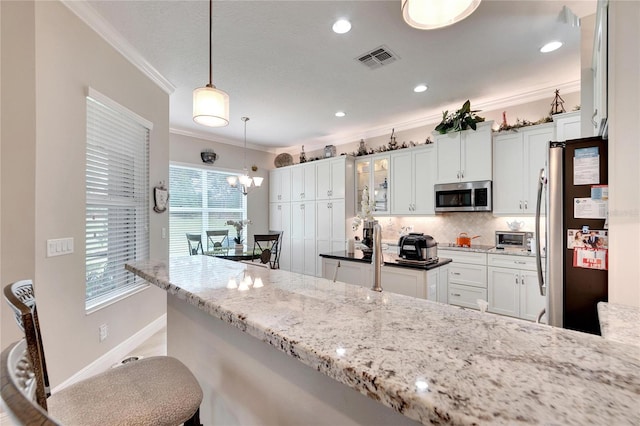 kitchen with white cabinets, appliances with stainless steel finishes, and hanging light fixtures