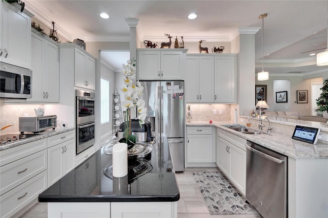 kitchen with crown molding, stainless steel appliances, sink, dark stone counters, and pendant lighting