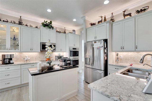 kitchen with dark stone counters, ornamental molding, backsplash, stainless steel appliances, and sink