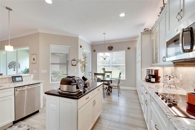 kitchen featuring pendant lighting, tasteful backsplash, glass insert cabinets, stainless steel appliances, and ornamental molding