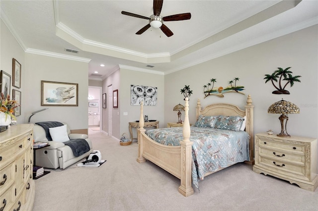 carpeted bedroom with ceiling fan, ornamental molding, ensuite bath, and a tray ceiling