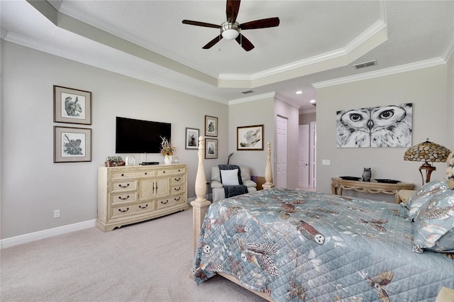 carpeted bedroom with a tray ceiling, a ceiling fan, baseboards, visible vents, and ornamental molding