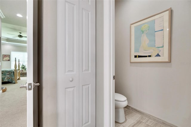 bathroom featuring baseboards, a closet, toilet, and ceiling fan