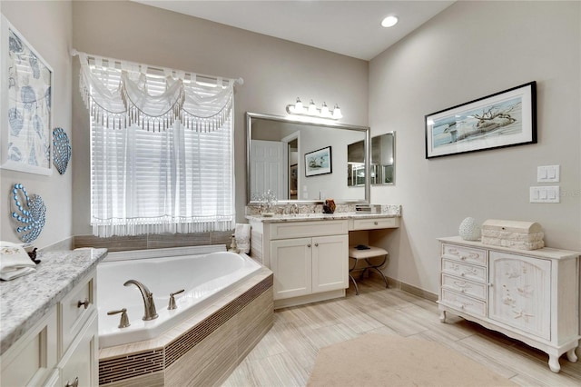 bathroom with tiled tub and vanity