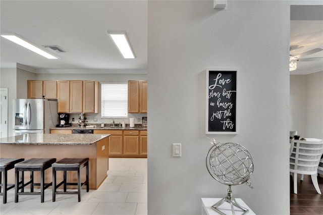 kitchen with light brown cabinets, light stone countertops, stainless steel appliances, crown molding, and ceiling fan