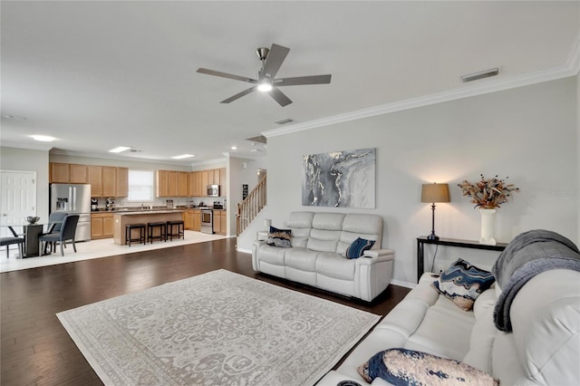 living room featuring ceiling fan, crown molding, and dark wood-type flooring