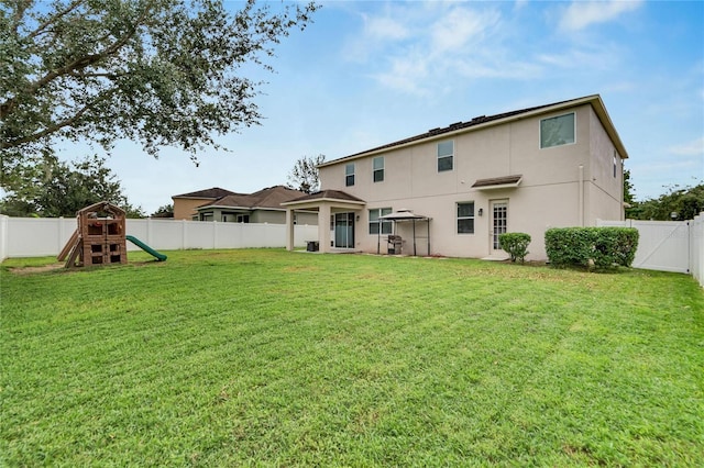 back of house featuring a playground and a yard