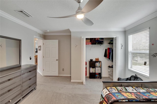 carpeted bedroom featuring ornamental molding, a closet, ceiling fan, and a textured ceiling