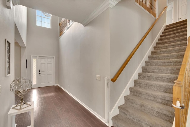 entrance foyer with a towering ceiling, dark hardwood / wood-style flooring, and crown molding