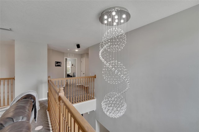 hallway with a textured ceiling, carpet, and a notable chandelier