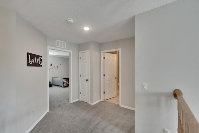 corridor featuring light carpet and a textured ceiling