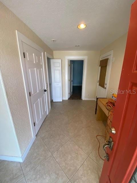 corridor with light tile patterned floors and a textured ceiling