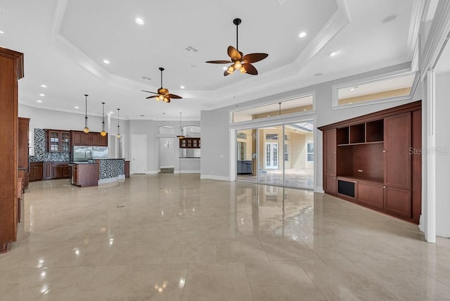 unfurnished living room featuring ceiling fan, a tray ceiling, and ornamental molding