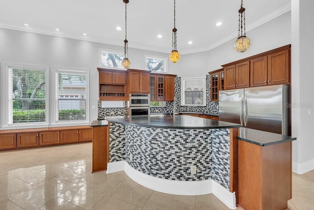 kitchen with appliances with stainless steel finishes, a center island with sink, ornamental molding, and pendant lighting