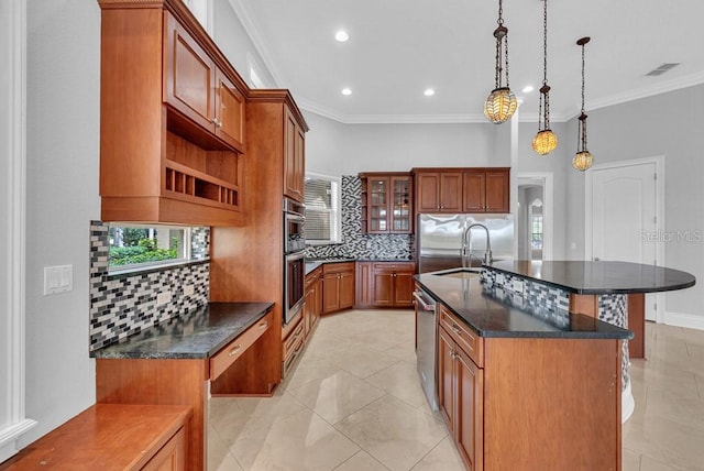 kitchen with tasteful backsplash, sink, an island with sink, hanging light fixtures, and light tile patterned floors