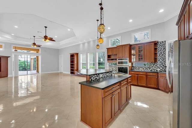 kitchen with appliances with stainless steel finishes, an island with sink, ceiling fan, decorative light fixtures, and ornamental molding