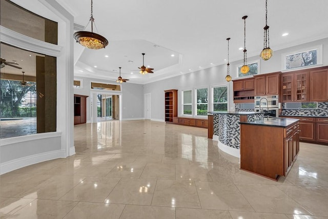 kitchen with a kitchen island with sink, pendant lighting, decorative backsplash, and ceiling fan