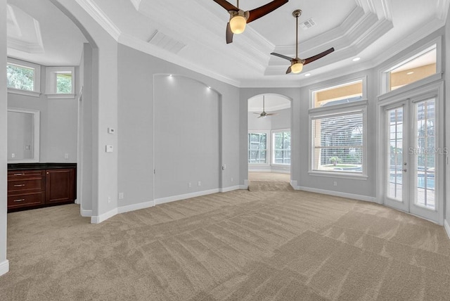 unfurnished living room with ceiling fan, a raised ceiling, light carpet, and ornamental molding