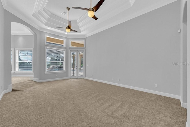 unfurnished living room featuring a raised ceiling, crown molding, ceiling fan, and light colored carpet