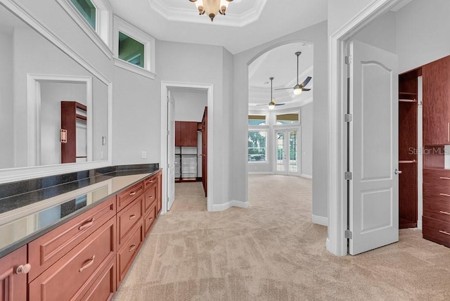 bathroom with ceiling fan, a towering ceiling, vanity, a raised ceiling, and crown molding