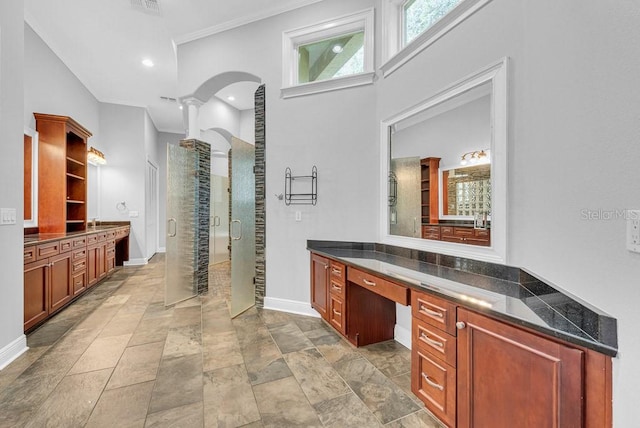 interior space with ornamental molding, vanity, and a shower with shower door