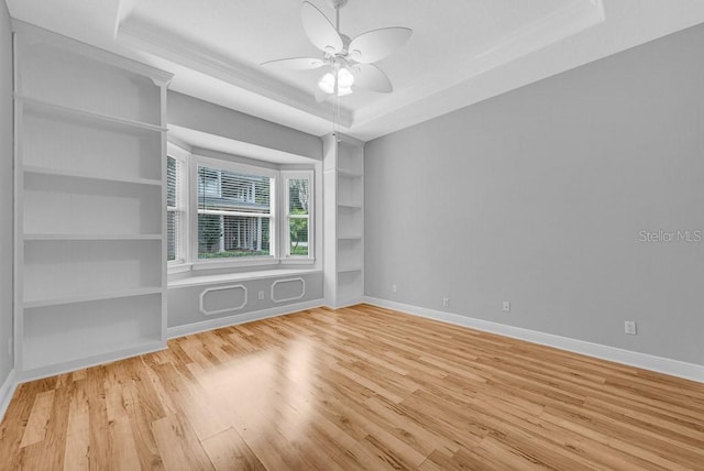 unfurnished room with light wood-type flooring, ceiling fan, and a raised ceiling