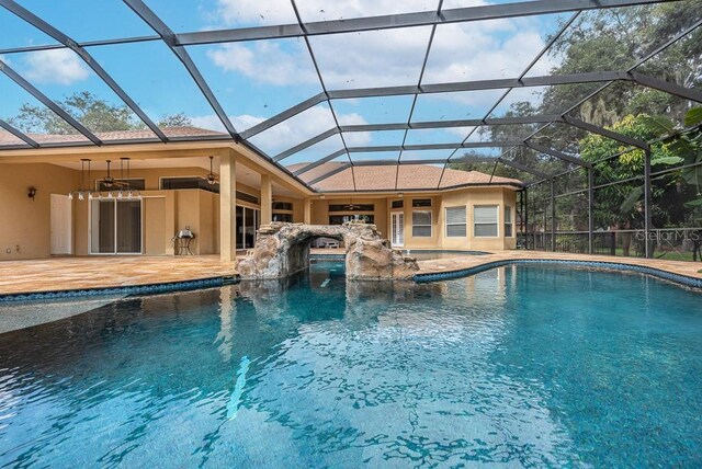 view of pool featuring glass enclosure, ceiling fan, and a patio area