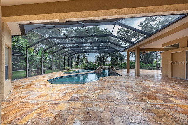 view of swimming pool featuring a patio, glass enclosure, and an in ground hot tub