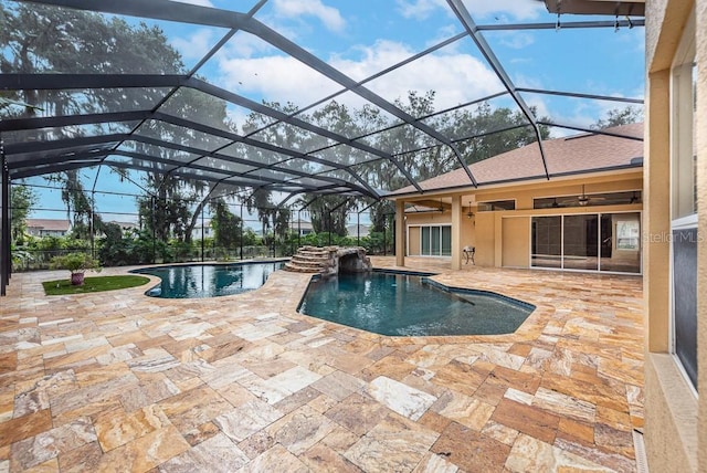 view of pool with pool water feature, glass enclosure, ceiling fan, and a patio area