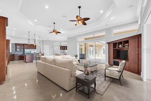 living room with crown molding, a tray ceiling, sink, and ceiling fan