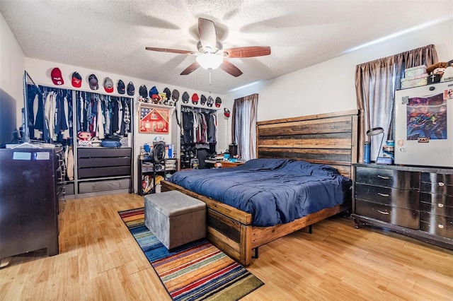 bedroom with hardwood / wood-style floors, ceiling fan, and a textured ceiling