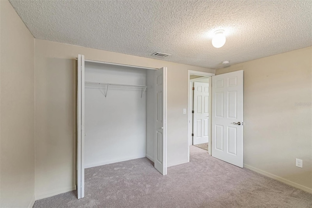 unfurnished bedroom with a textured ceiling, light colored carpet, and a closet