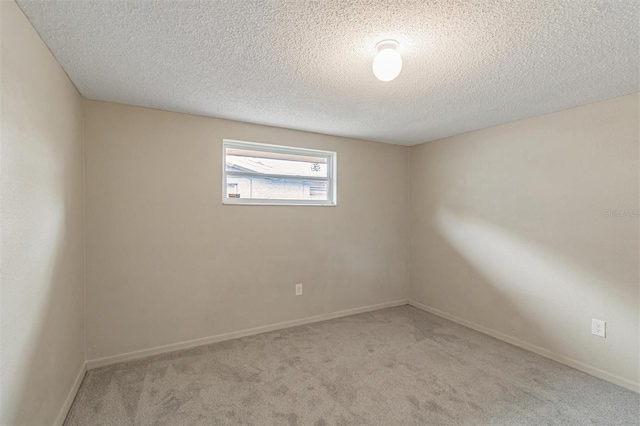 spare room featuring a textured ceiling and light colored carpet